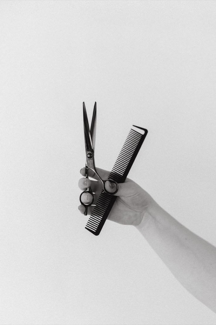 Schere und Kamm in der Hand